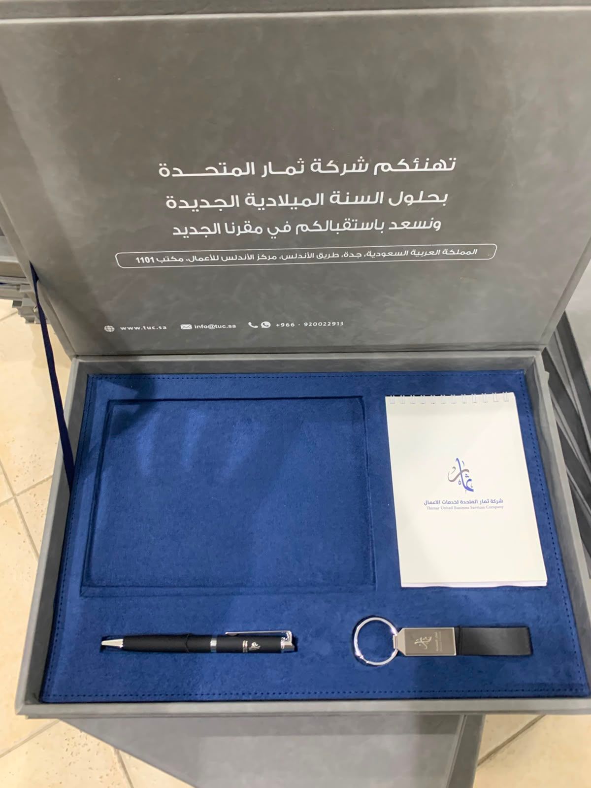 علبة هدية مؤسسية: مفكرة وقلم وميدالية وذاكرة USB في صينية مخملية زرقاء، جدة