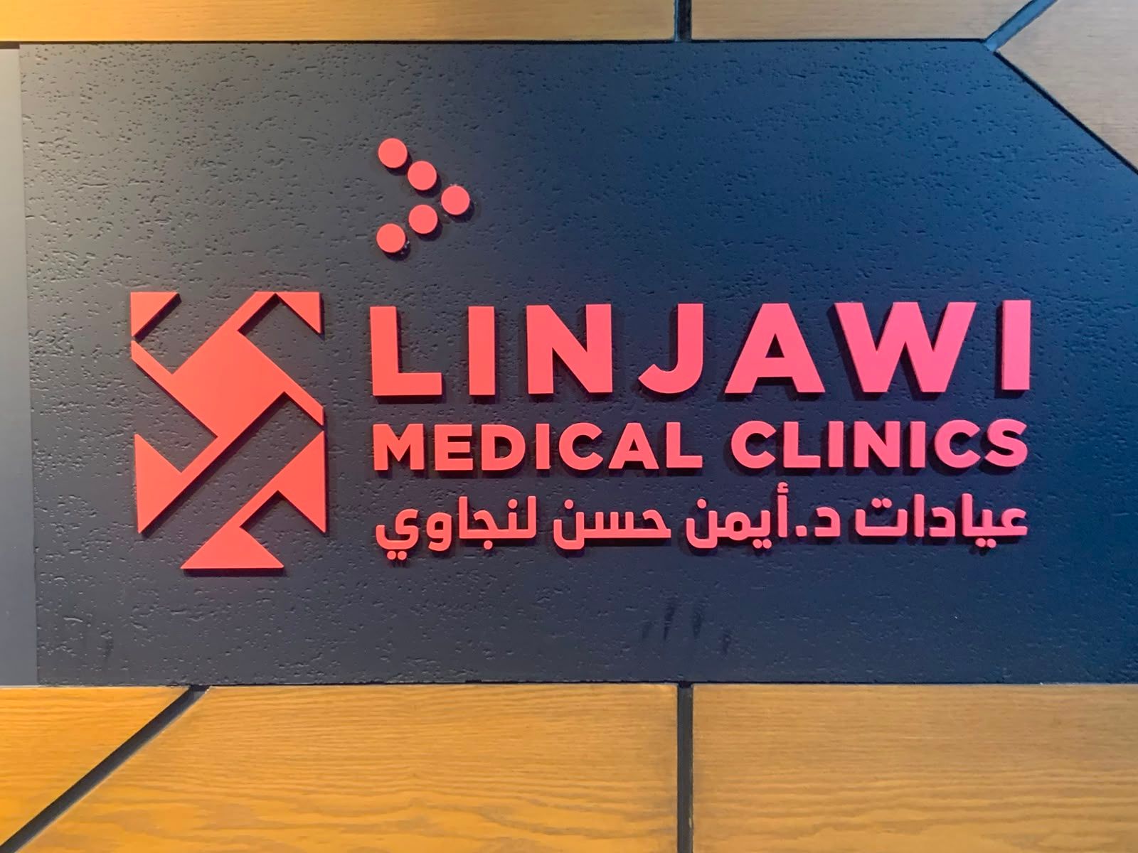حروف وشعار بارز باللون الأحمر لعيادات طبية على لوح جداري داكن، جدة